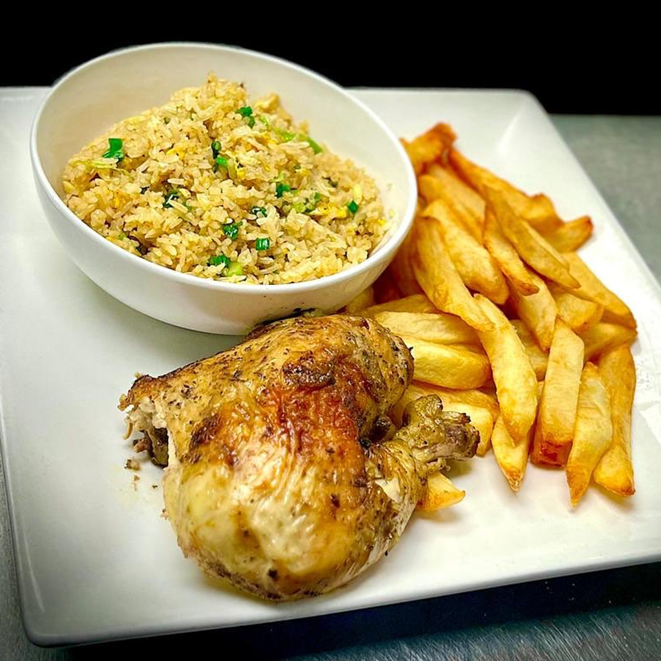 Peruvian quarter rotisserie chicken with golden fries and a bowl of fried rice.